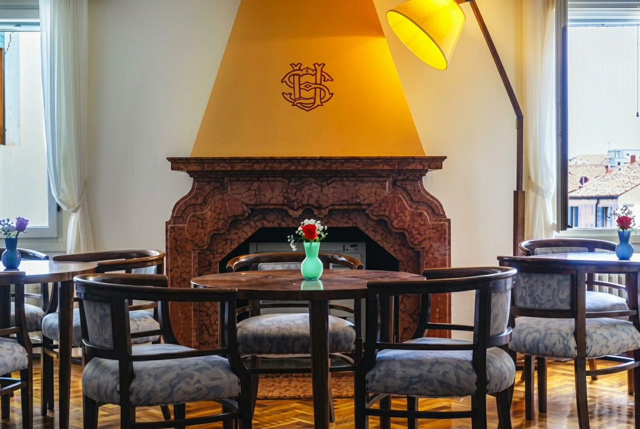 Sala del circolo con camino in marmo, monogramma sul cappello e tavoli con sedie in legno